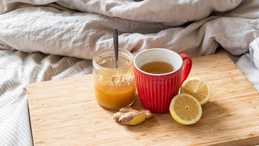 Eine Teetasse mit Honig, Ingwer und Zitrone auf einem Bett | Bild: BR / Leon Baatz