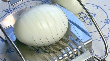 Ein Ei liegt in einem Eierschneider. | Bild: 	mauritius images / Pitopia / Liz Collet