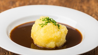 ein Kartoffelknödel mit Soße in einem weißen Teller | Bild: mauritius images / Pitopia / Bernd Jürgens