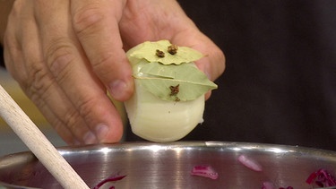 Eine Nelke, die durch ein Lorbeerblatt an einer halben geschälten Zwiebel gepickt wurde | Bild: Wir in Bayern