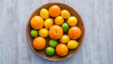 aus der Vogelsperspektive fotografiert: ein Bastkorb gefüllt mit Orangen, Zitronen und Limonen | Bild: mauritius images / Cavan Images / Rafa Fernandez