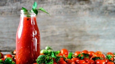 Eine Glasflasche mit Tomatensoße; daneben liegen Cocktailtomaten | Bild: mauritius images / Alicja neumiler / Alamy / Alamy Stock Photos