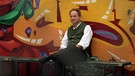 Pfarrer Schießler sitzt vor einer Graffiti-Wand. | Bild: BR