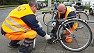 Symbolbild: 2 Männer flexen das Schloss eines abgestellten Schrott-Fahrrads auf. | Bild: picture alliance / dpa | Jochen Lübke
